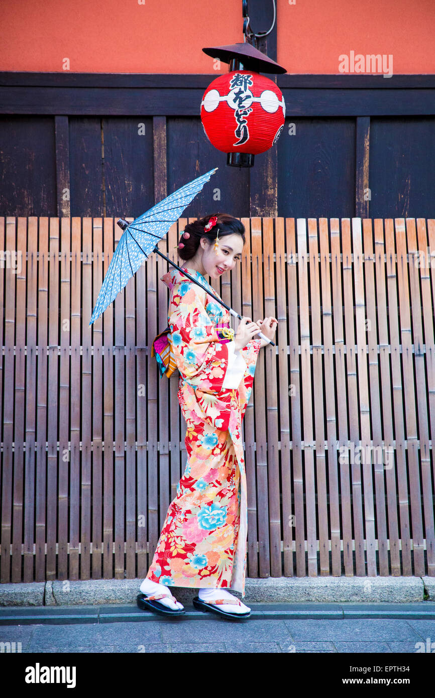 girl dressed as a geisha holding a parasol in Japan Stock Photo