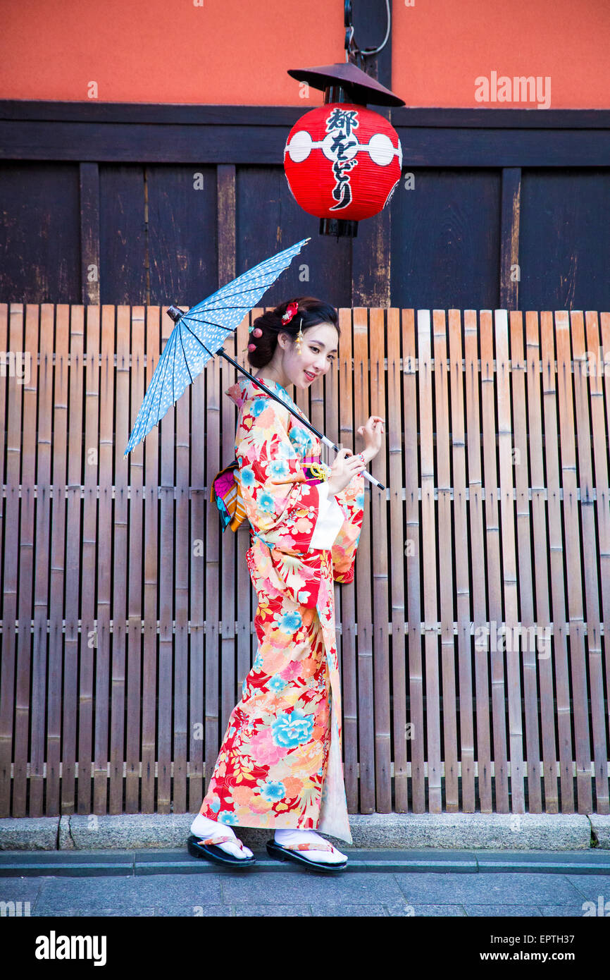 girl dressed as a geisha holding a parasol in Japan Stock Photo