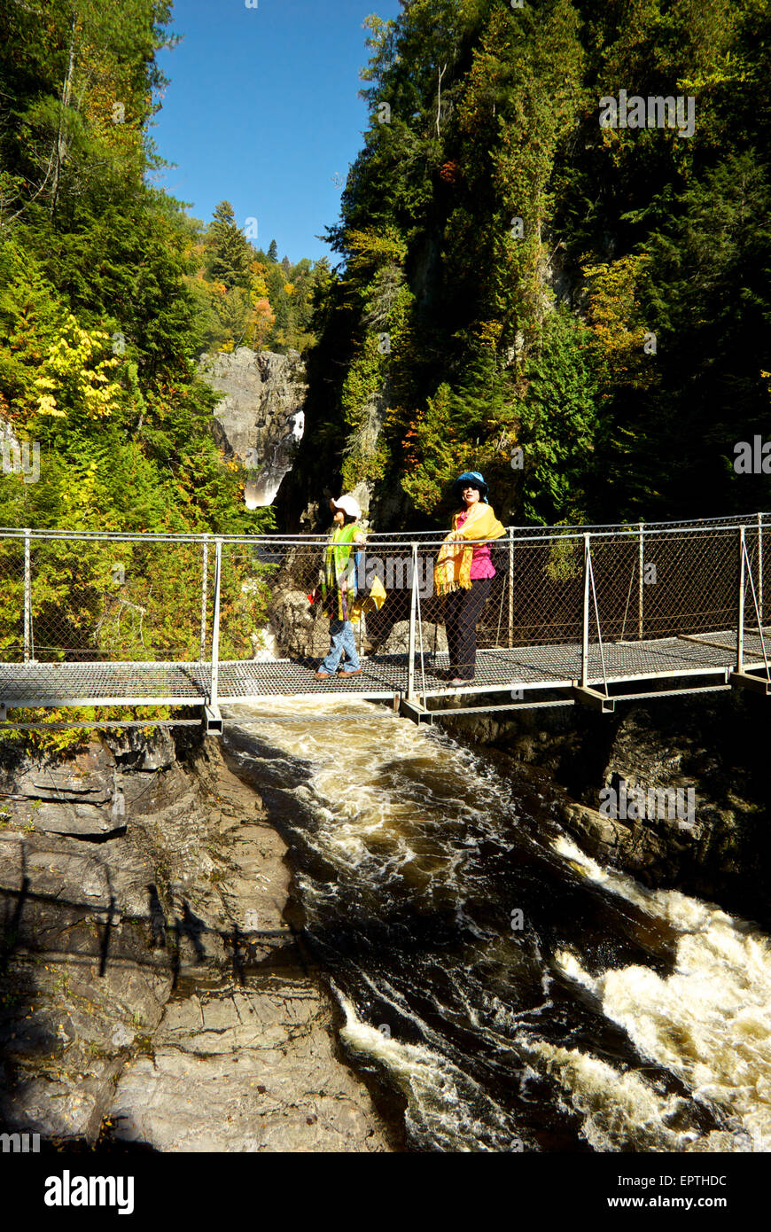 Asian visitors crossing Canyon Ste Anne River pedestrian suspension bridge Stock Photo
