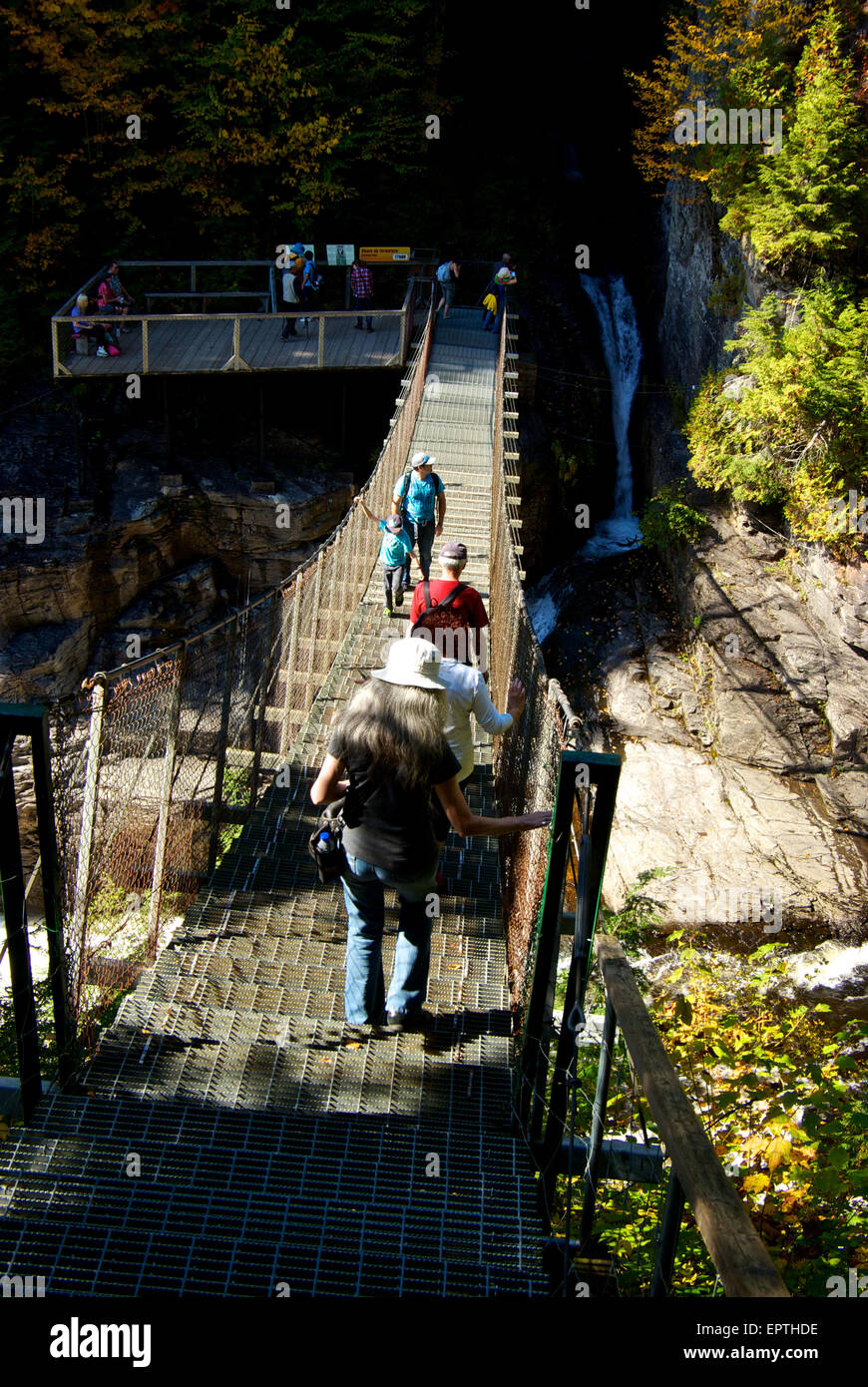 Pedestrians on suspension bridge over river gorge waterfall Canyon Ste Anne Park Stock Photo