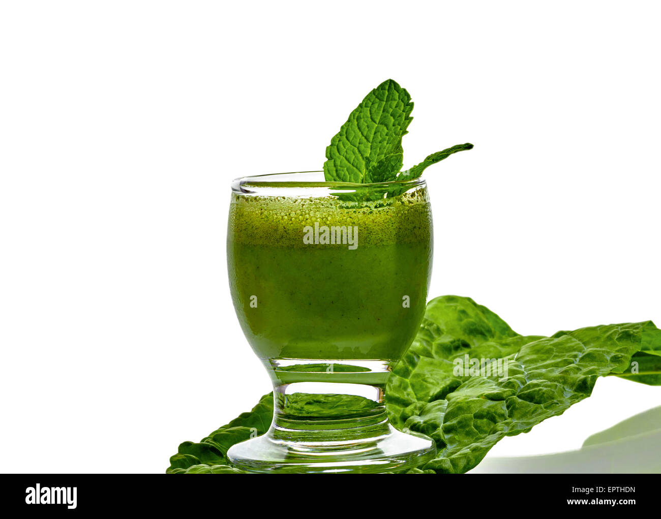 Green vegetable smoothie with peppermint leaf sitting on top of kale