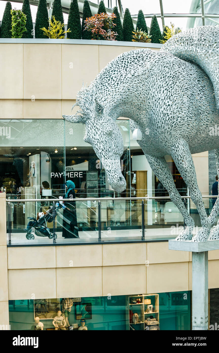 EQUUS ALTUS Andy Scott Sculpture of Pack Horse mounted Ten Meters High in Leeds Trinity Shopping Center with Woman Pushing Pram Stock Photo