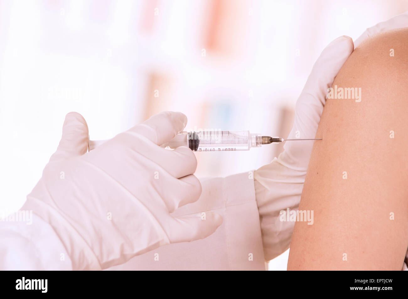 closeup of doctor's hand with injection holding patients shoulder Stock Photo
