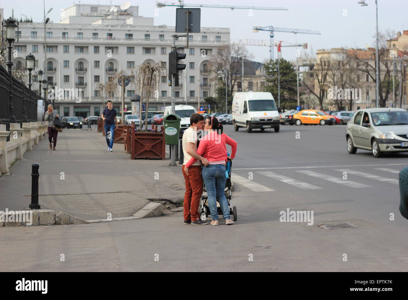 A Couple with a baby kissing on the side of the road, Bucharest, Romania Stock Photo