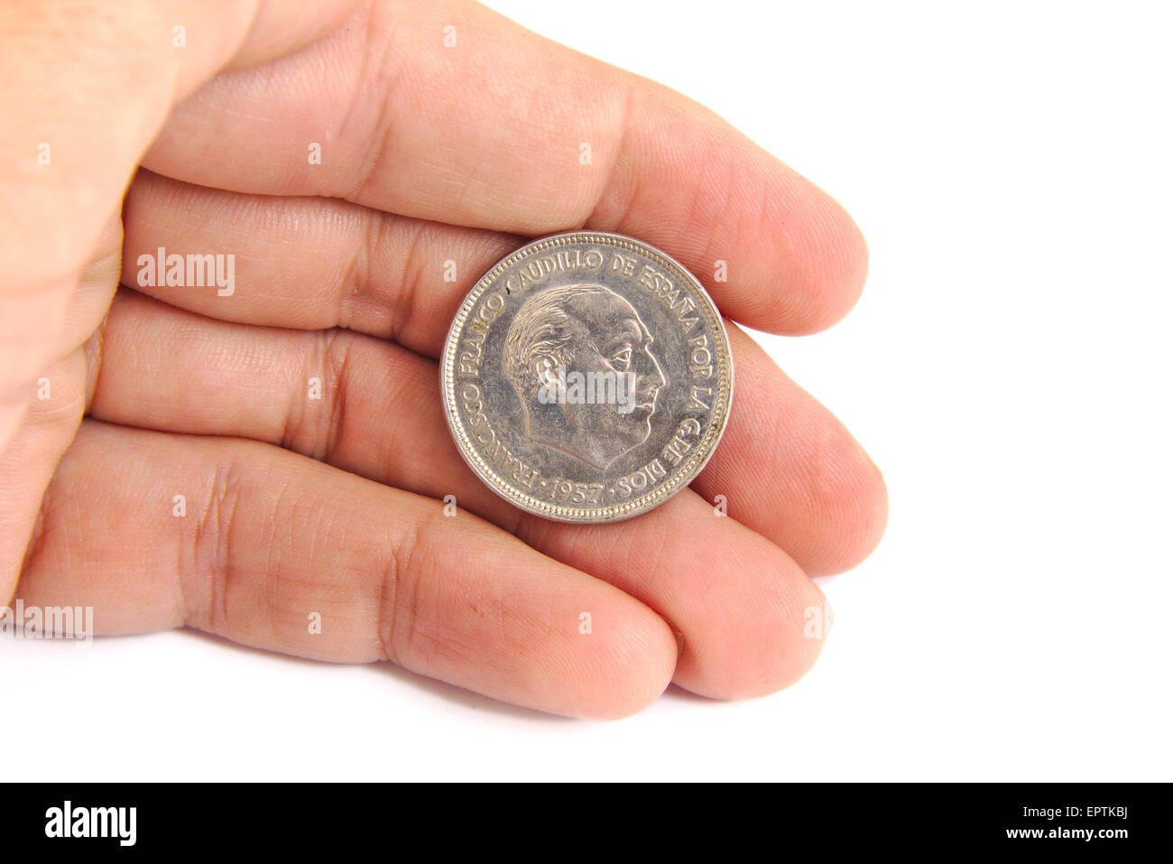 Caucasian man hand holding an old Spanish coin of 50 pesetas showing Franco dictator face on a white background. 1957 Stock Photo