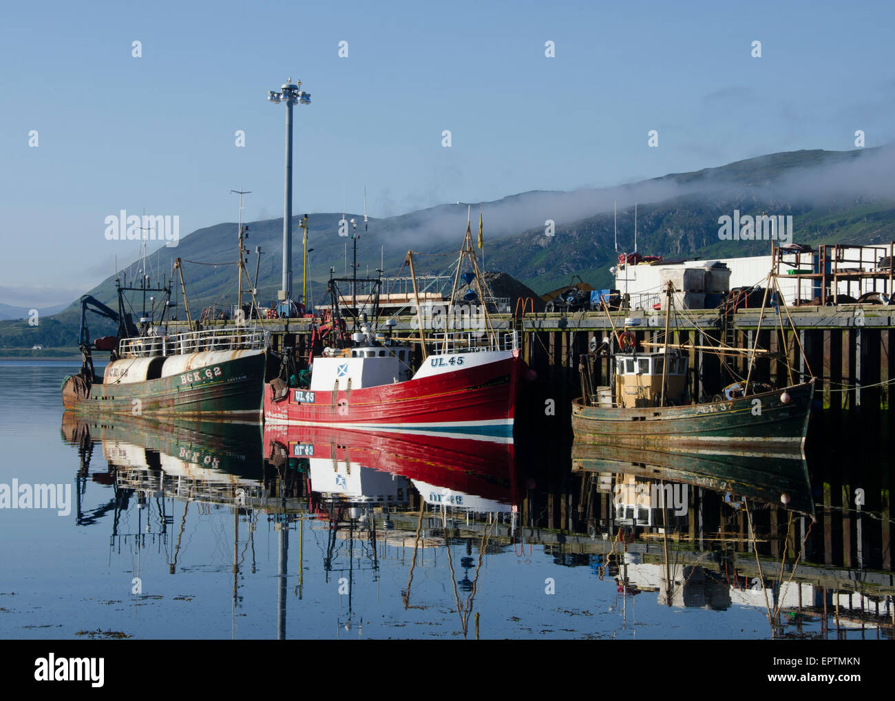 Fishing vessels reflecting in the waters of Ullapool harbor in the Scottish Highlands. Stock Photo