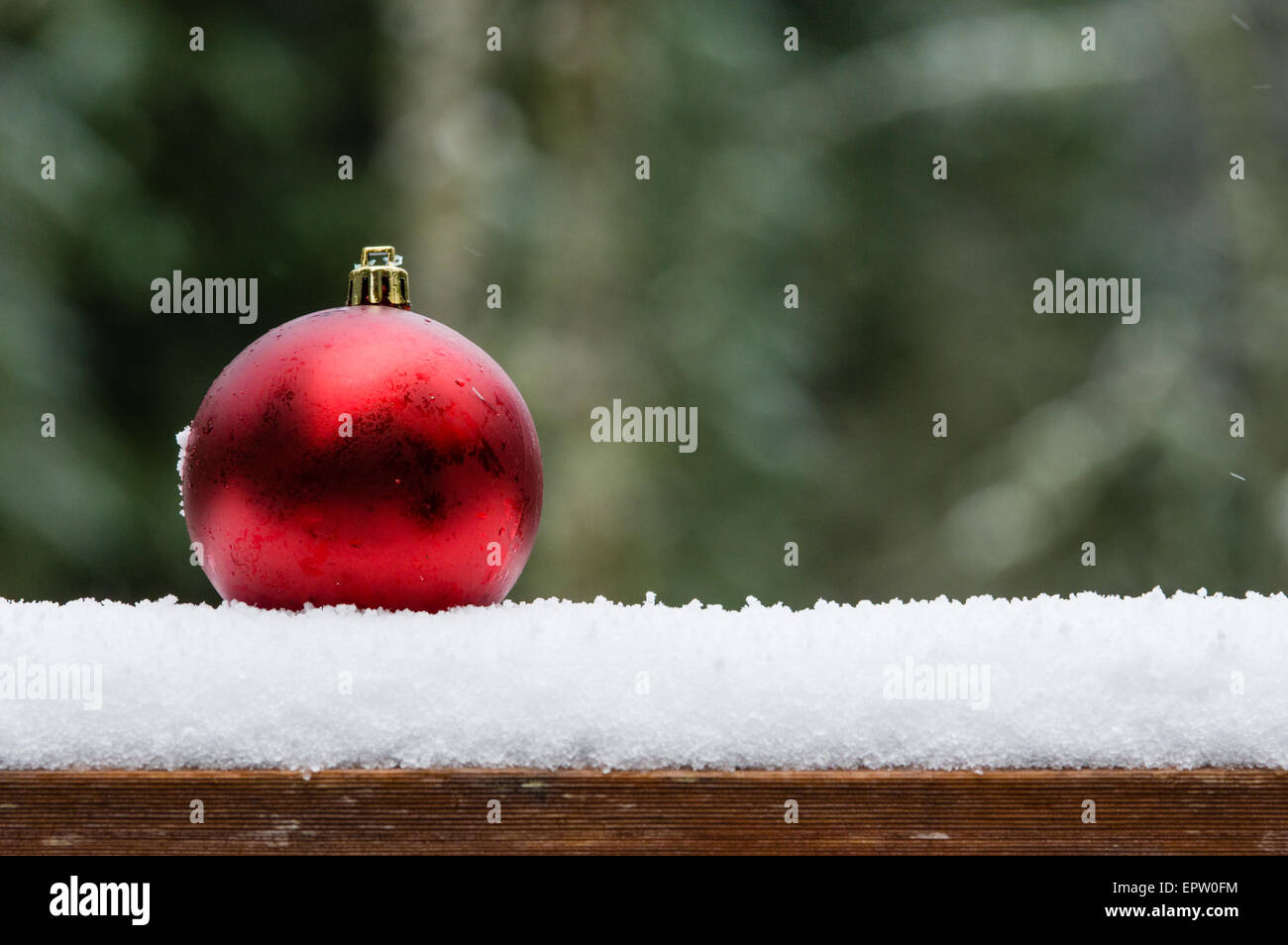 Single red ornament on snow covered railing Stock Photo - Alamy