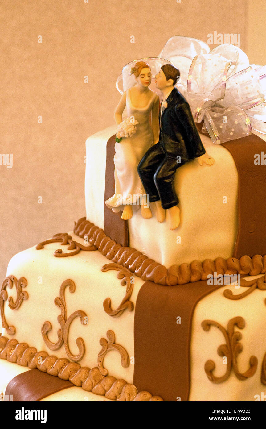 Kissing bride and groom figurines top a wedding cake with chocolate frosting Stock Photo