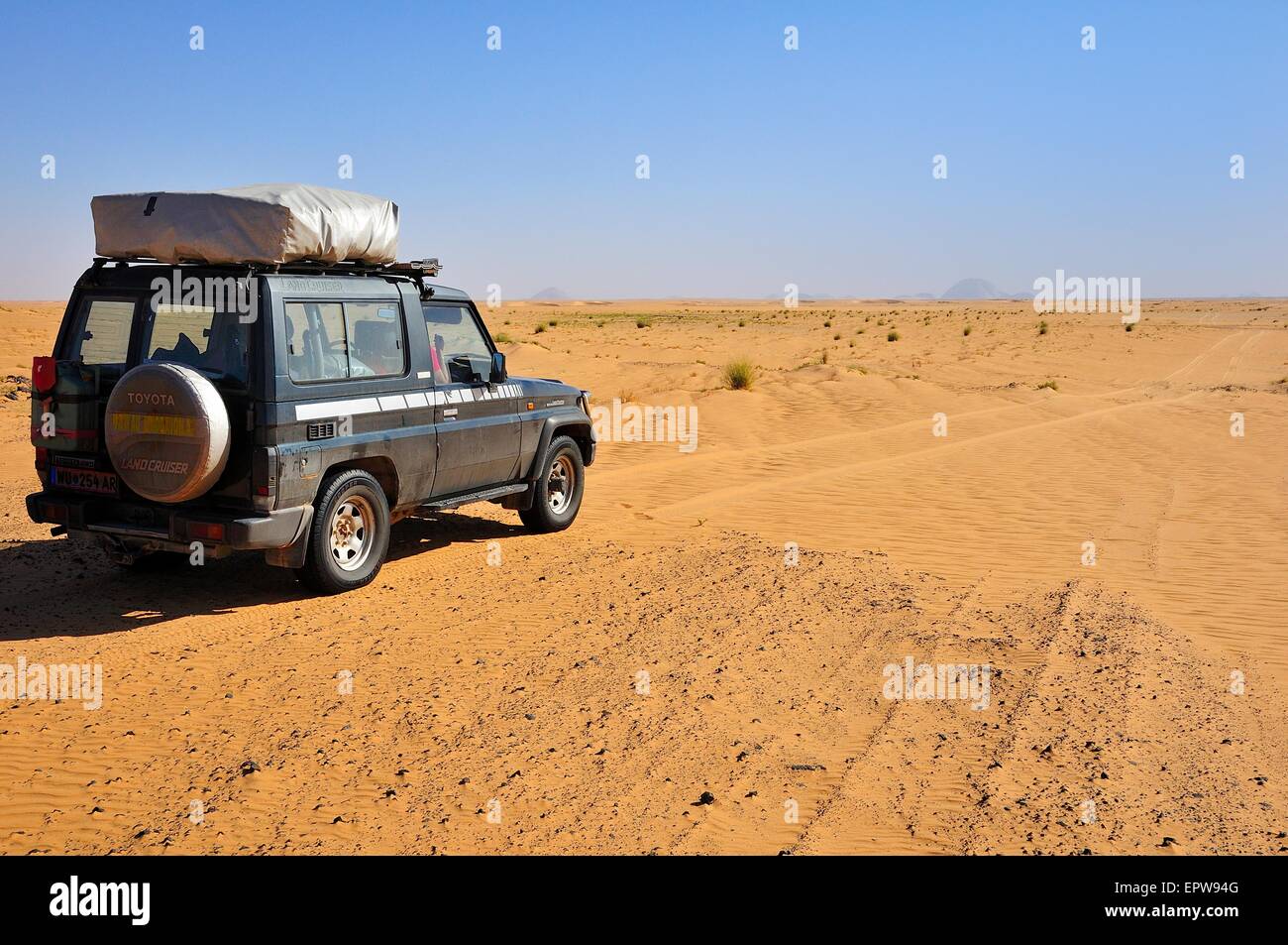 All-terrain vehicle with a roof tent on the dirt track, Aicha monolith behind, Adrar region, Mauritania Stock Photo
