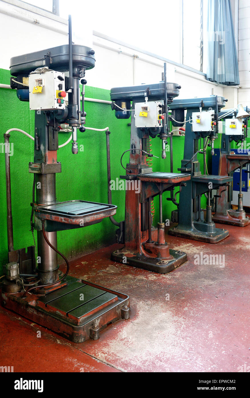 Row of freestanding bench drills in a factory or engineering workshop for industrial manufacturing and production Stock Photo