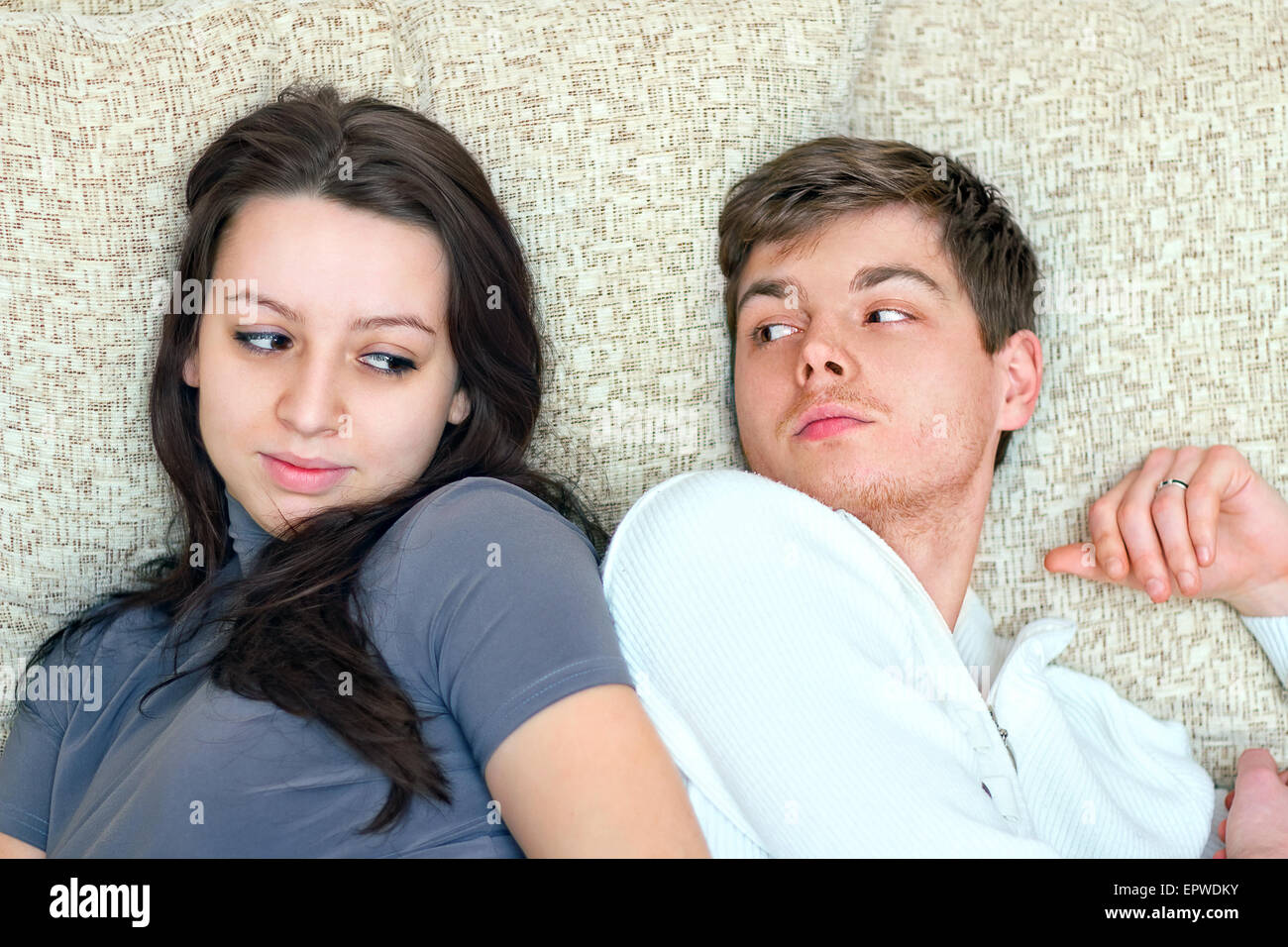 young boy and girl look at each other while lying on bed Stock Photo