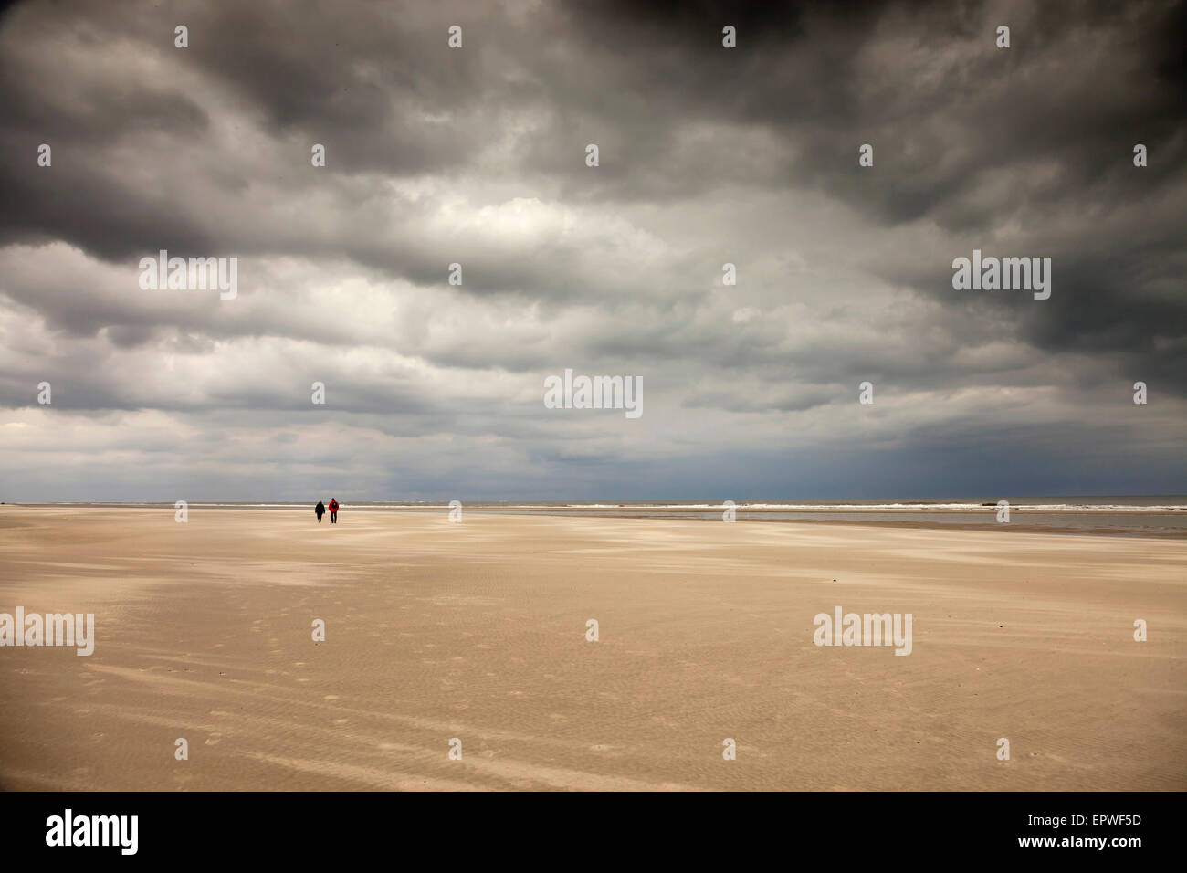 couple having a walk at the low tide beach short before a thunderstorm,    East Frisian Island Spiekeroog, Lower Saxony, Germany Stock Photo