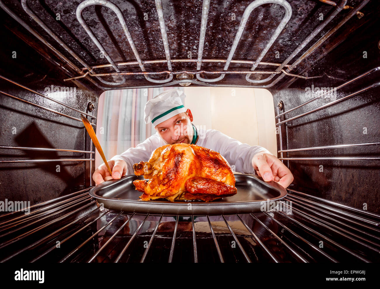 Chef prepares roast chicken (focus on chicken) in the oven, view from