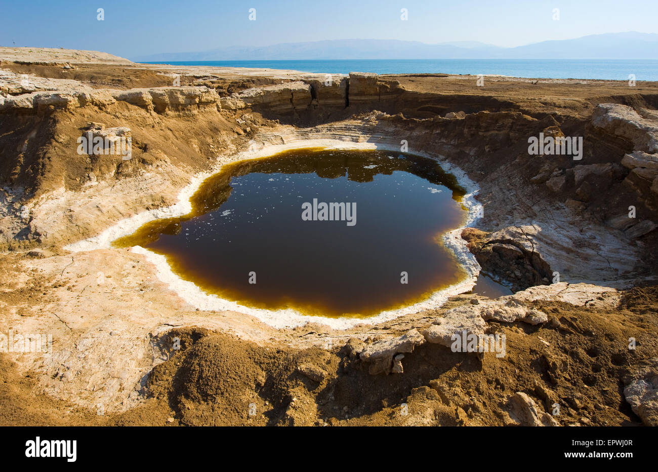 Sinkhole or open pit on the shore's of the dead sea at the end of the summer when the water level is at it's lowest Stock Photo