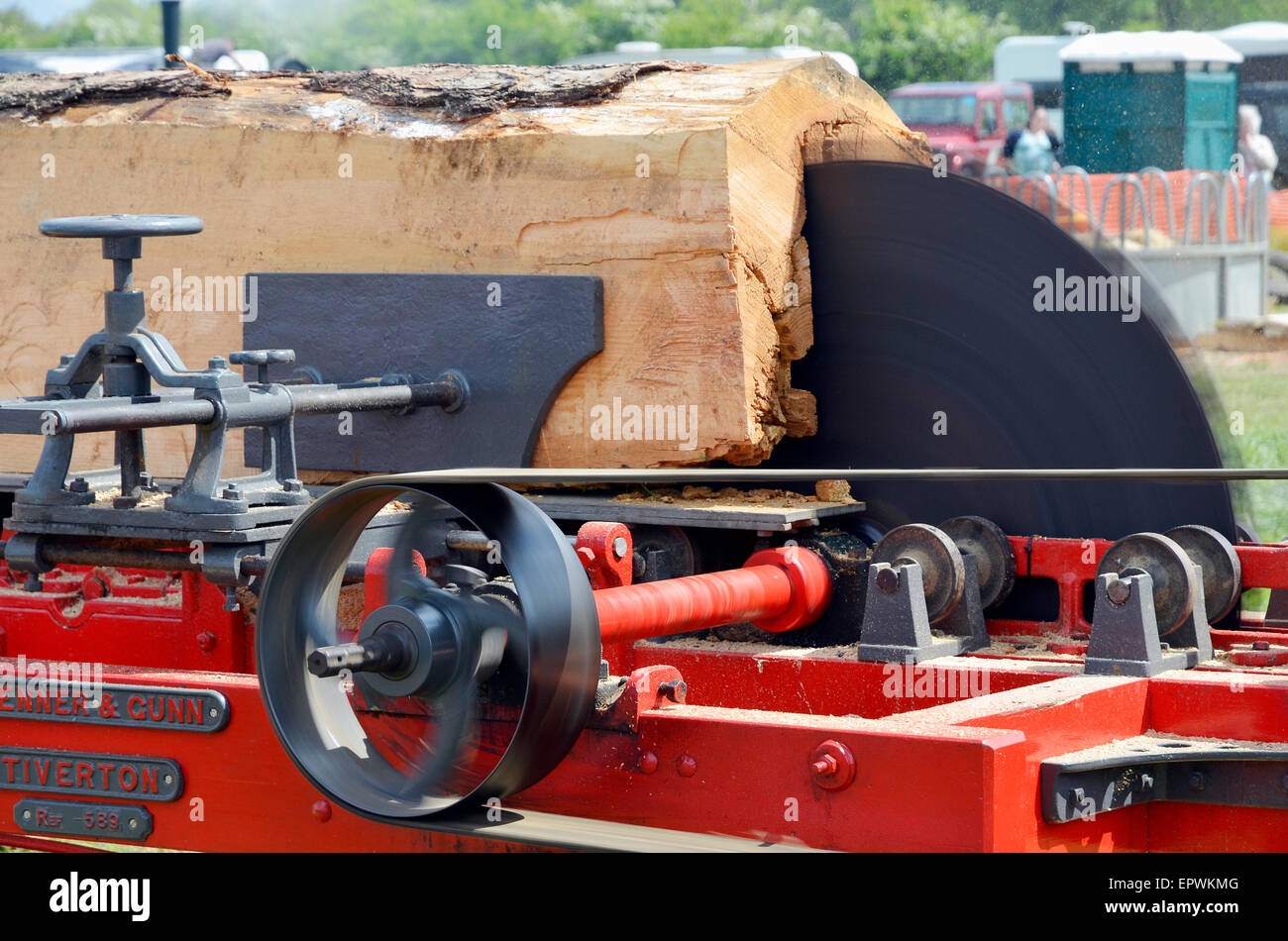 A large steam-powered circular saw cuts into a tree-trunk on a portable saw bench demonstrated at a country fair. Stock Photo