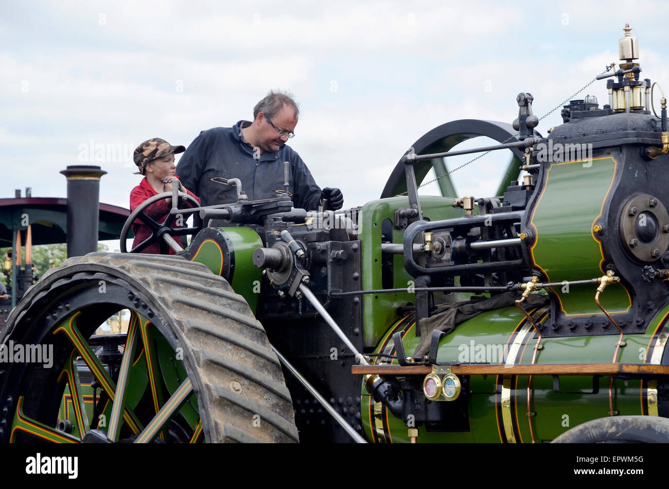 Starting them young - a small boy carefully steers a steam traction engine supervised carefully by an adult. Stock Photo