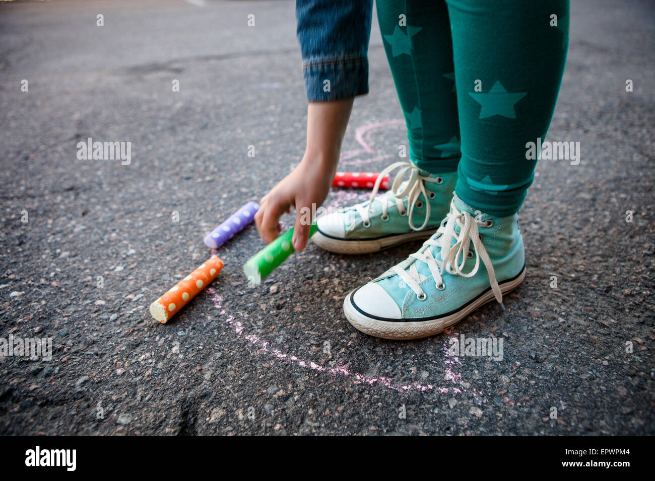 Girl drawing with street chalk on asphalt outdoors Stock Photo