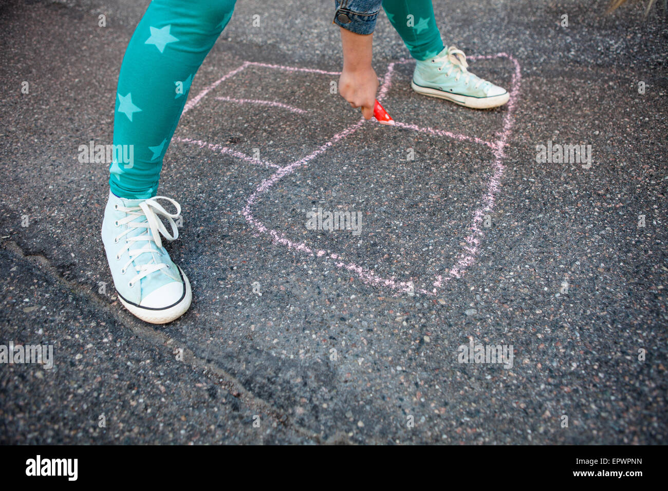 Girl drawing a hopscotch on asphalt with street chalk outdoors Stock Photo