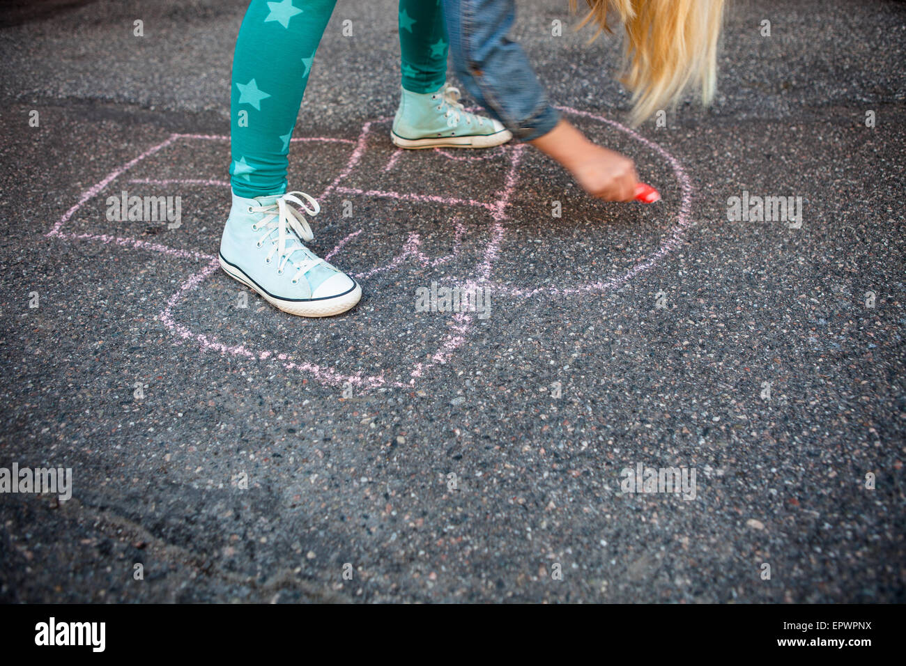 Girl drawing a hopscotch on asphalt with street chalk Stock Photo