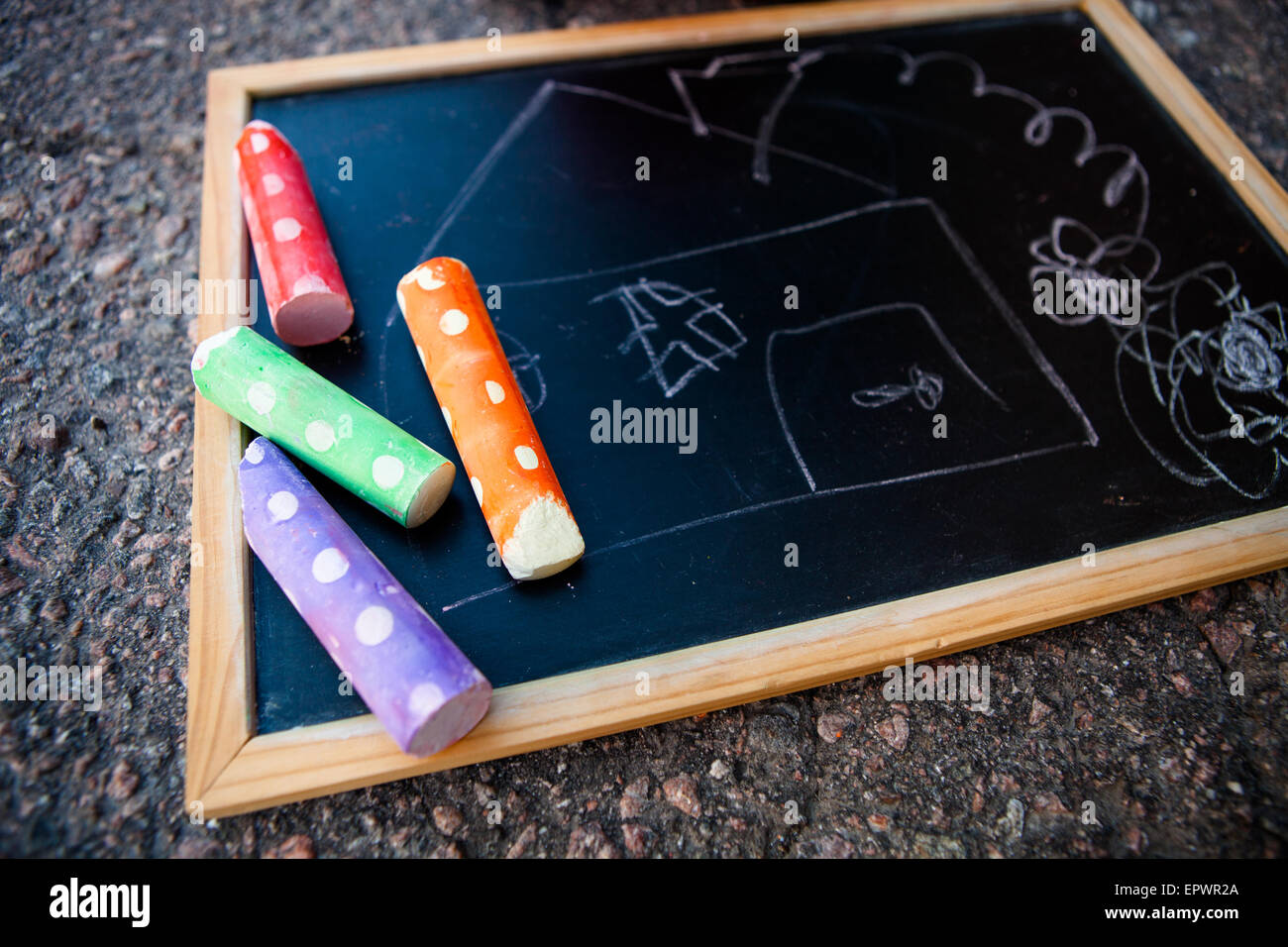 Chalkboard with a picture of a house and colorful street chalk Stock Photo