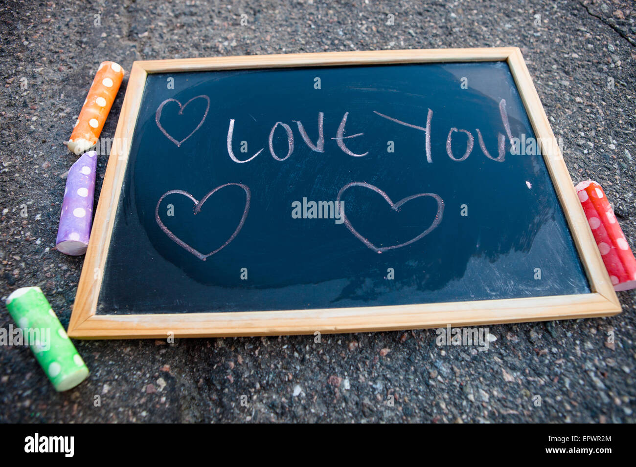 I love you message with hearts on chalkboard with colorful street chalk Stock Photo
