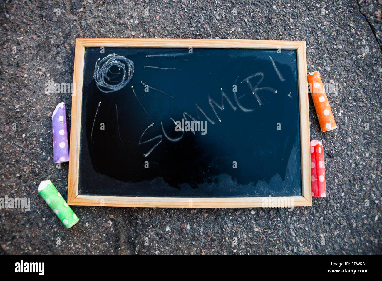 Chalkboard with word summer written on it and a sun with colorful street chalk Stock Photo