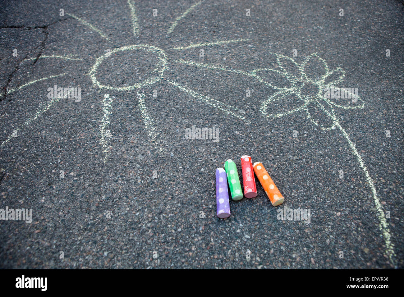 Sun and flower drawn to asphalt with colorful street chalk Stock Photo