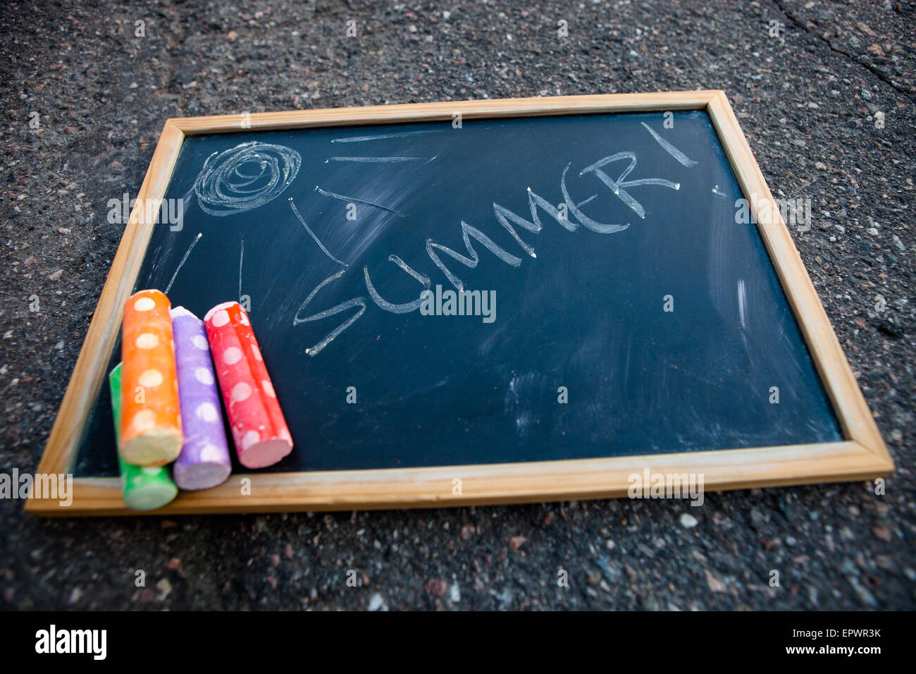 Chalkboar that has summer written on it with a picture of sun and colorful street chalk Stock Photo