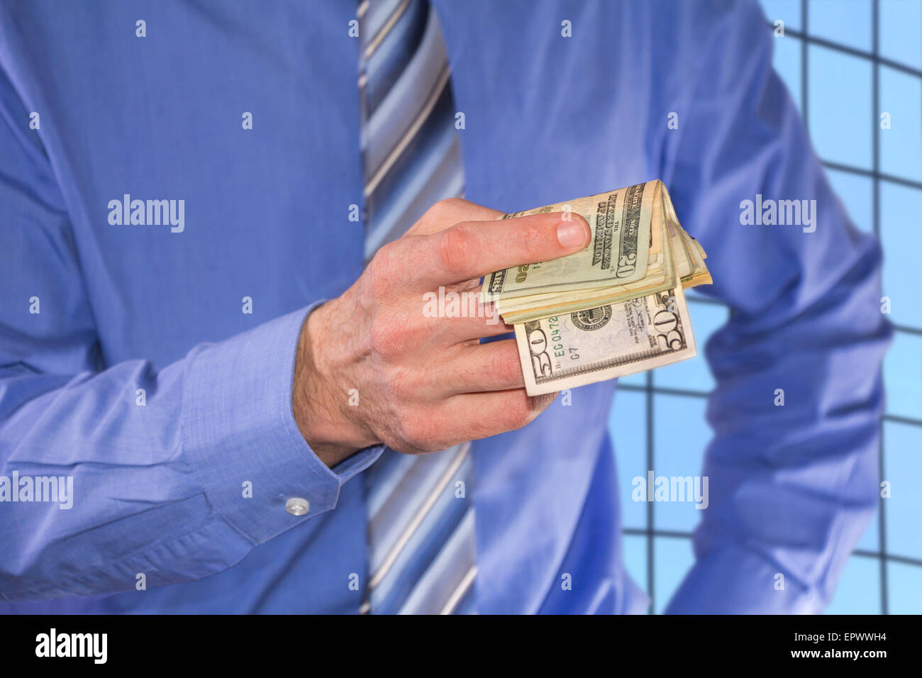 Man in a blue shirt, is paying in dollars banknotes Stock Photo