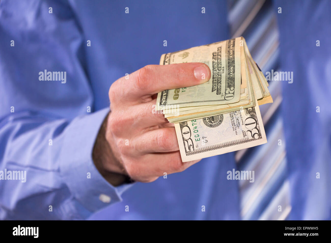 Man in a blue shirt, is paying in dollars banknotes Stock Photo