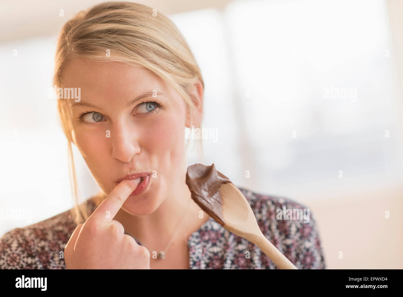 Woman licking batter off spoon Stock Photo