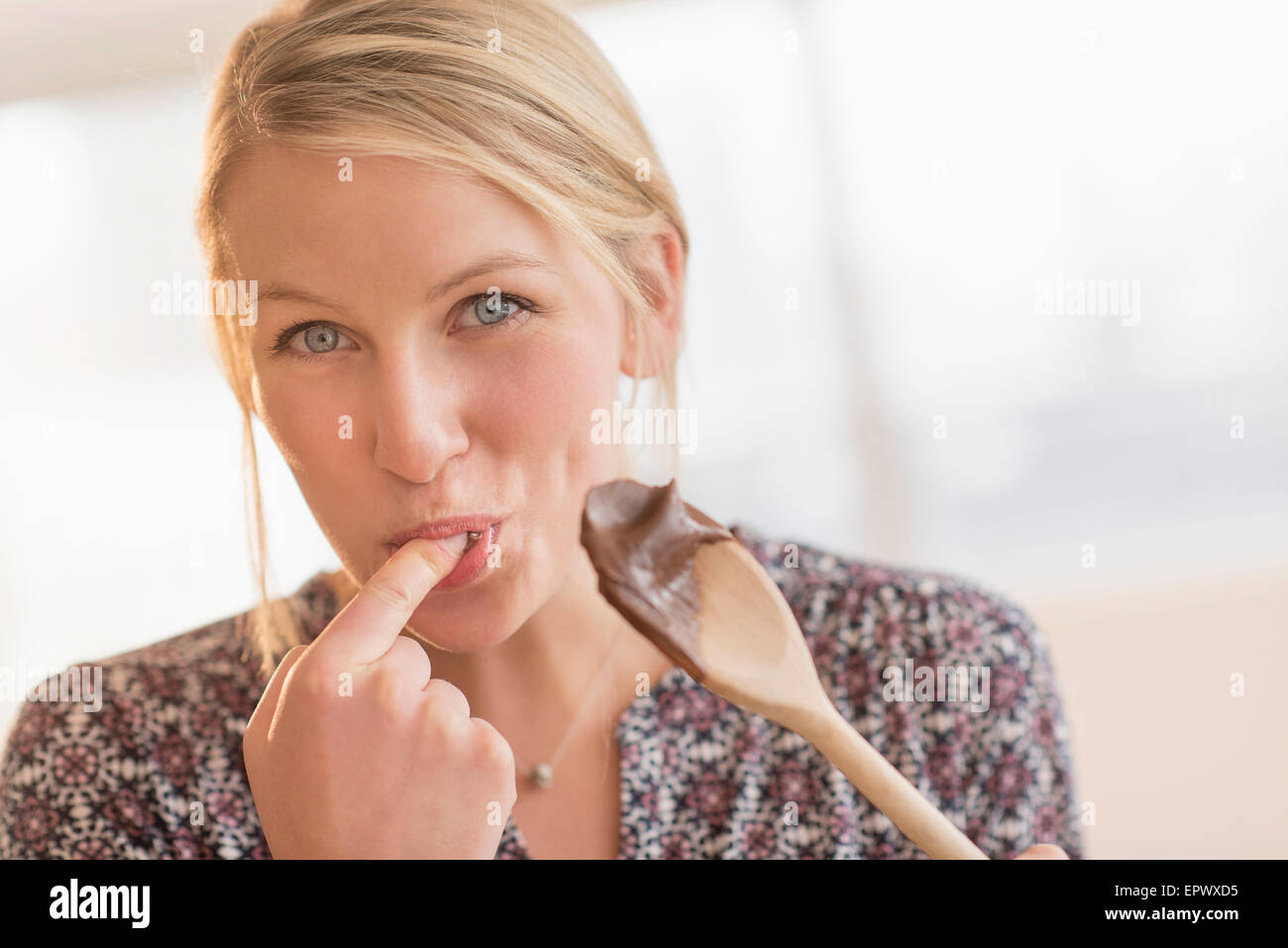 Woman licking batter off spoon Stock Photo