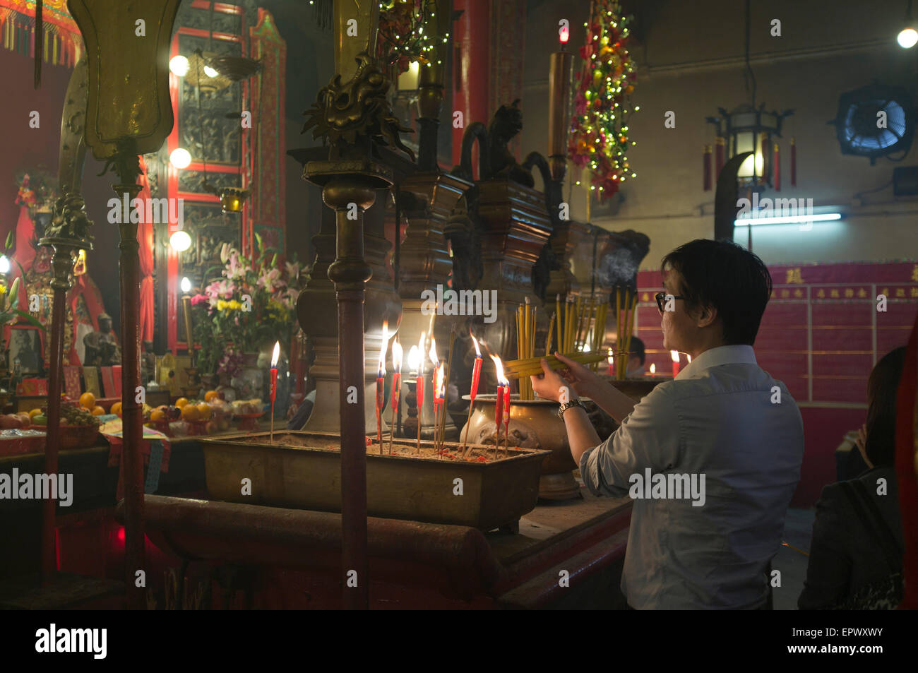 dh Man Mo Temple SHEUNG WAN HONG KONG Chinese man lighting joss sticks temple china scene temples joss stick tao incense prayer burning buddhist Stock Photo