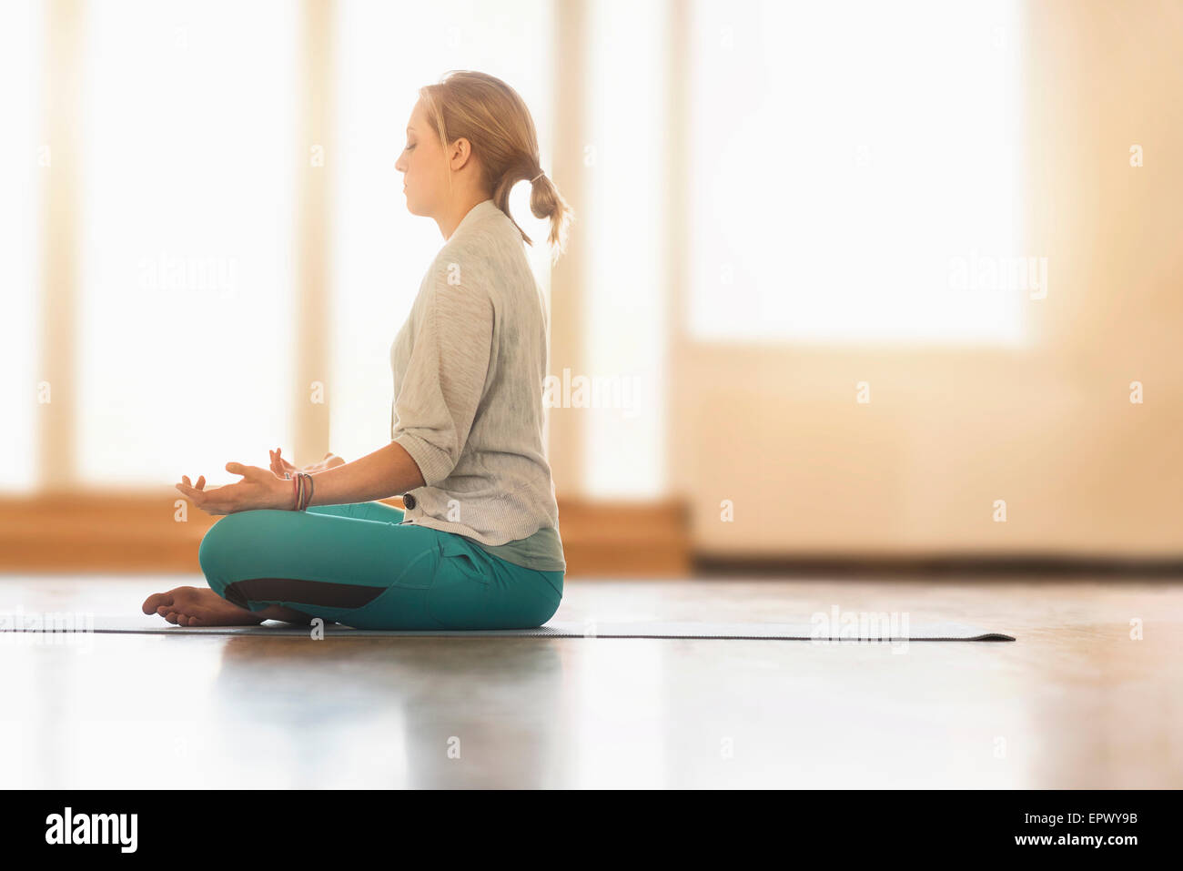 Woman meditating on floor Stock Photo - Alamy
