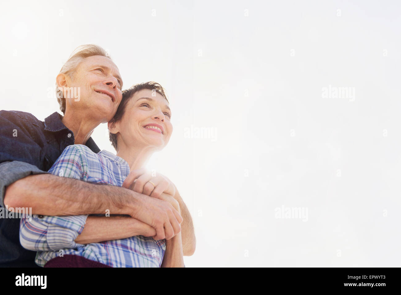 Smiling senior couple embracing in sunlight Stock Photo