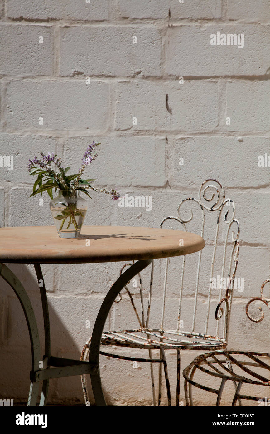 Marble cafe style table with wrought iron chairs and vase of lavender