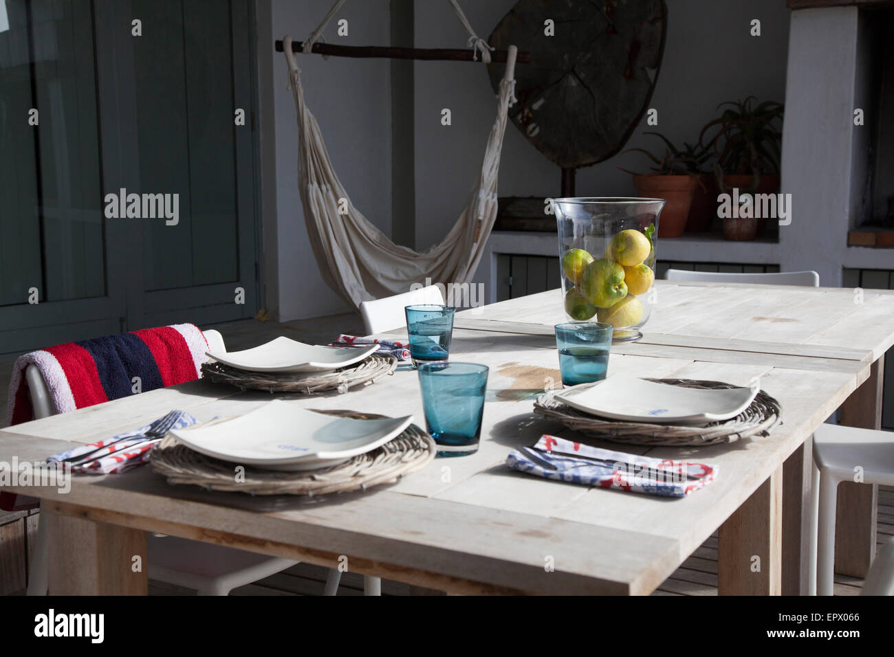Patio table set for lunch with cane underplates, qhite plates