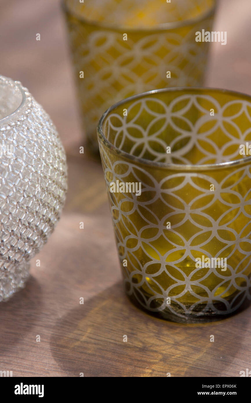 Green patterned and silver bead covered glass tea light holders on wooden surface in South African beach house Stock Photo