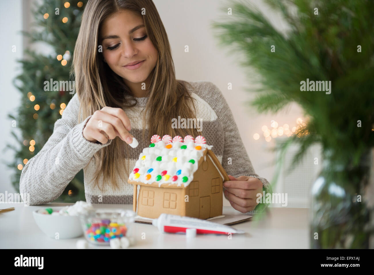 Young woman preparing gingerbread house Stock Photo