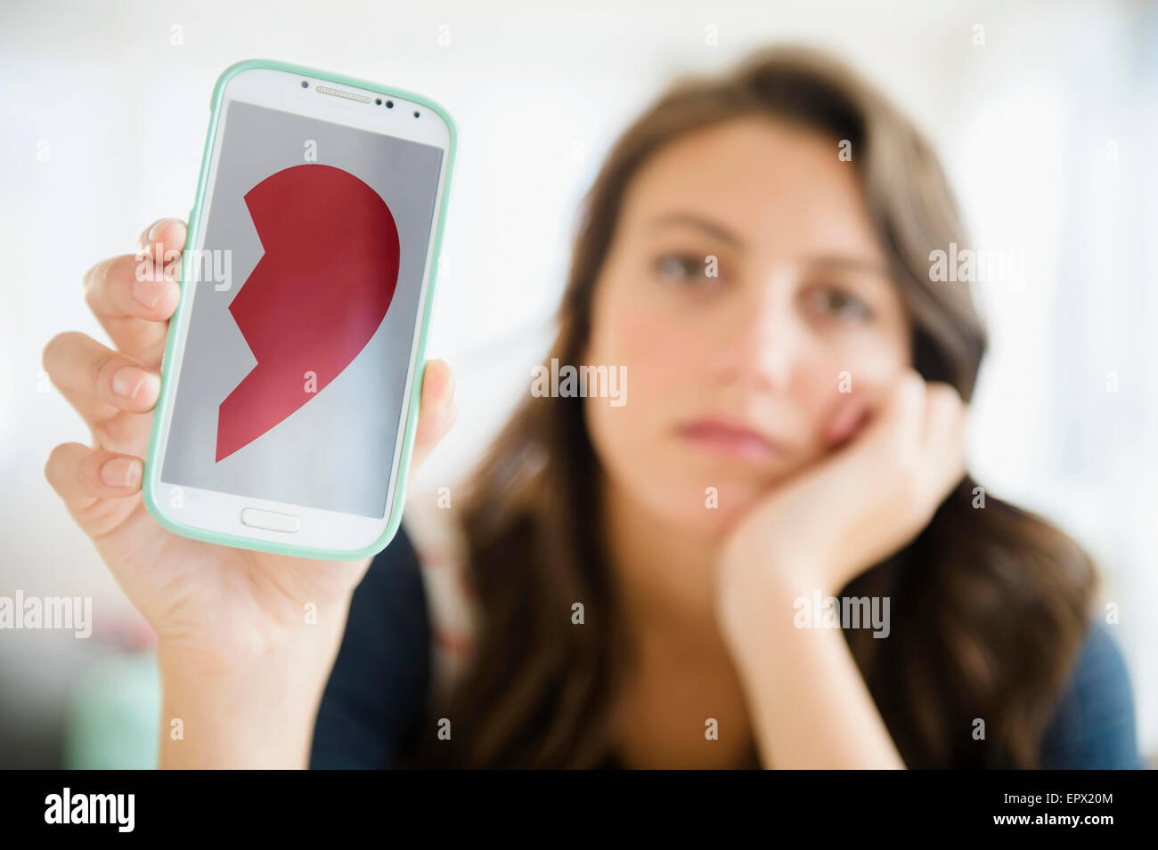 Woman showing image of broken heart on her smartphone Stock Photo