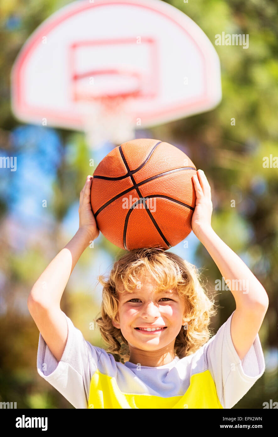 Boy (8-9) caring basketball on head Stock Photo