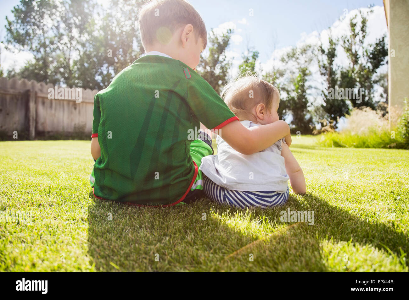 USA, Colorado, Brother (6-7) and sister (6-11months) sitting in grass Stock Photo
