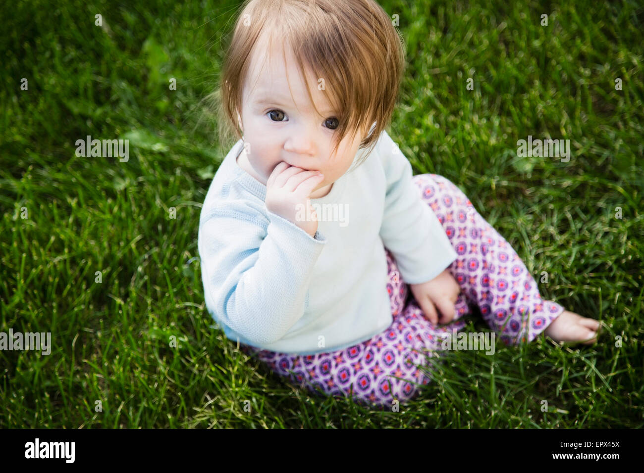 Portrait of baby girl (6-11 months) with hand in mouth Stock Photo