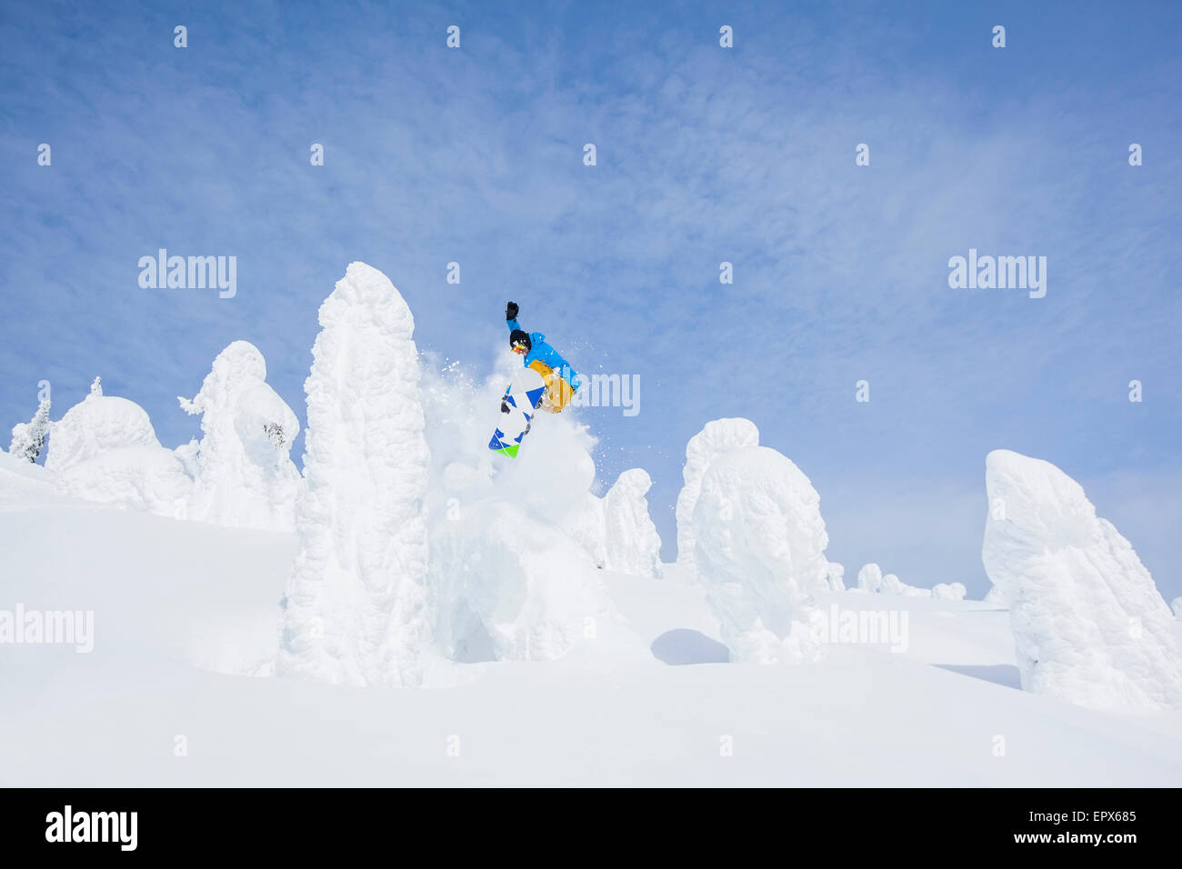 USA, Montana, Whitefish, Snowboarder jumping over snowy tree Stock Photo