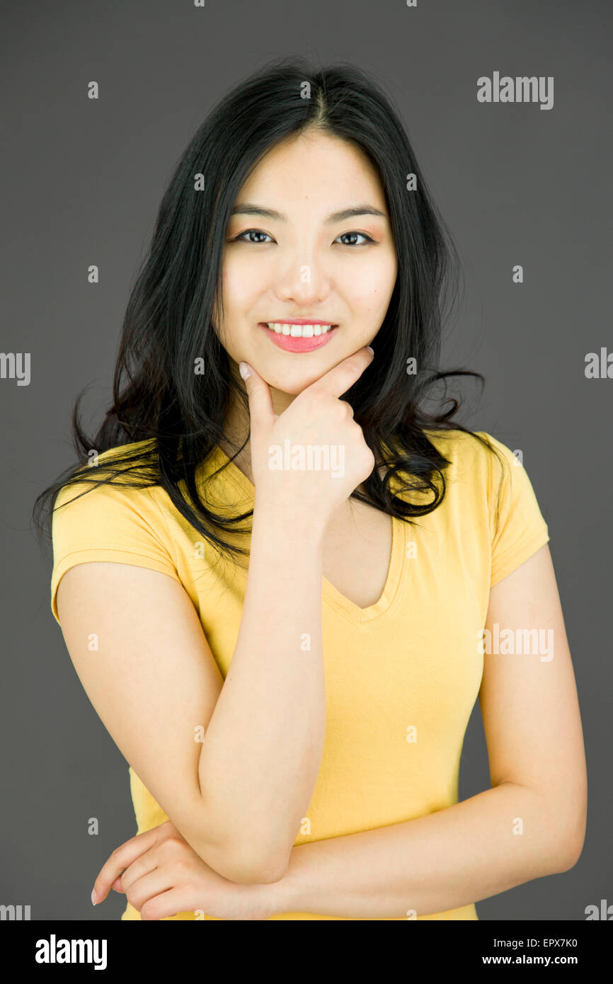 Young Asian woman smiling with hand on chin Stock Photo - Alamy