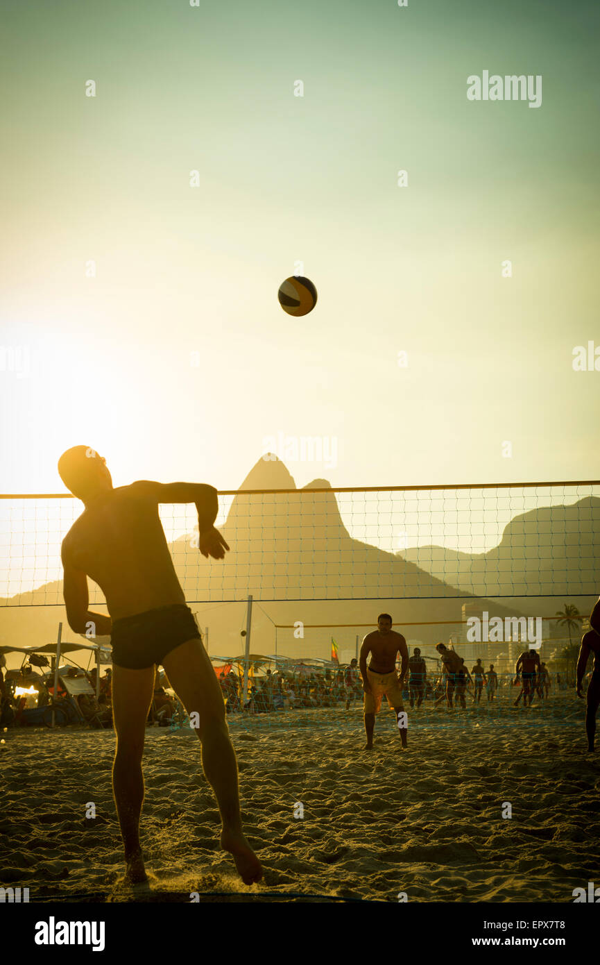 RIO DE JANEIRO, BRAZIL - FEBRUARY 01, 2014: Young carioca Brazilians play a game of beach volleyball at Posto 9 at sunset. Stock Photo