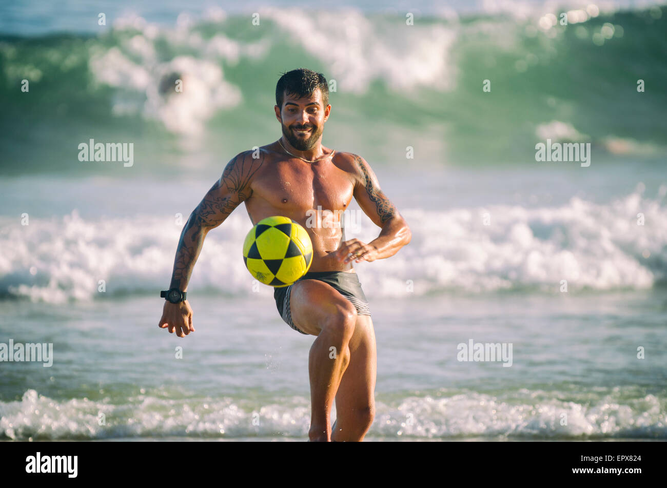 RIO DE JANEIRO, BRAZIL - JANUARY 28, 2014: Muscular young Brazilian man plays a game of altinho keepy uppy at Posto 9 in Ipanema Stock Photo