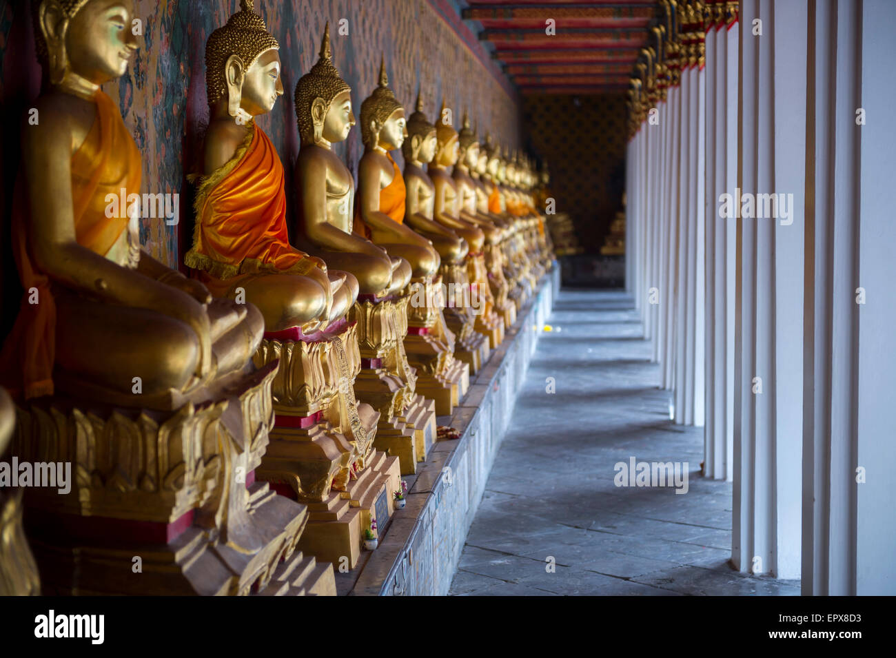 Row of golden seated buddhas in front of decorative wall in a Buddhist ...