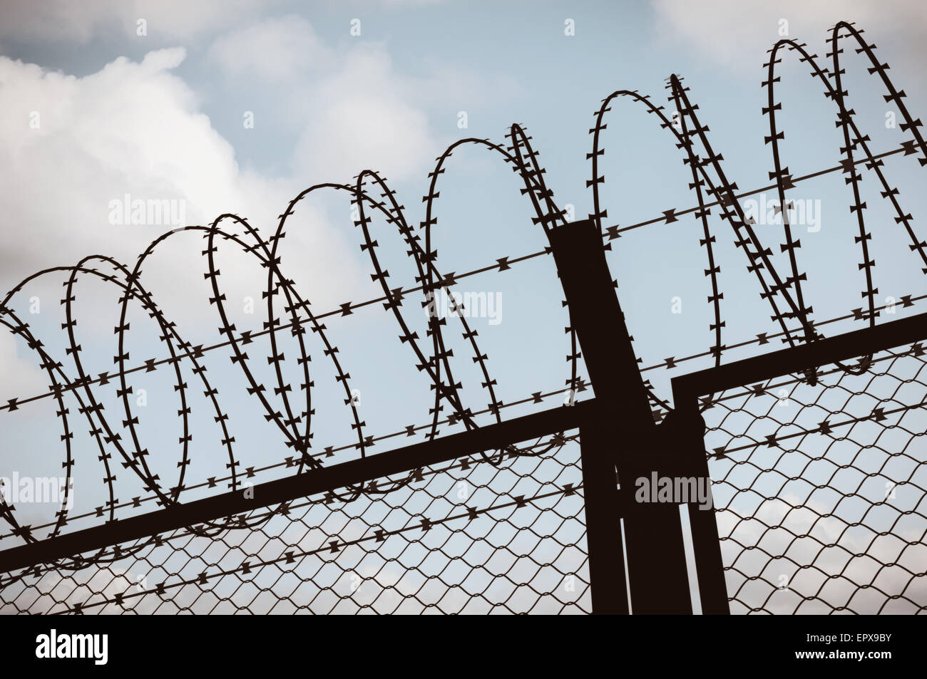 Fence with a barbed wire, silhouette on blue sky Stock Photo