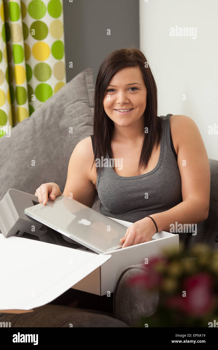 Young woman taking out a new laptop from it's packaging. Stock Photo